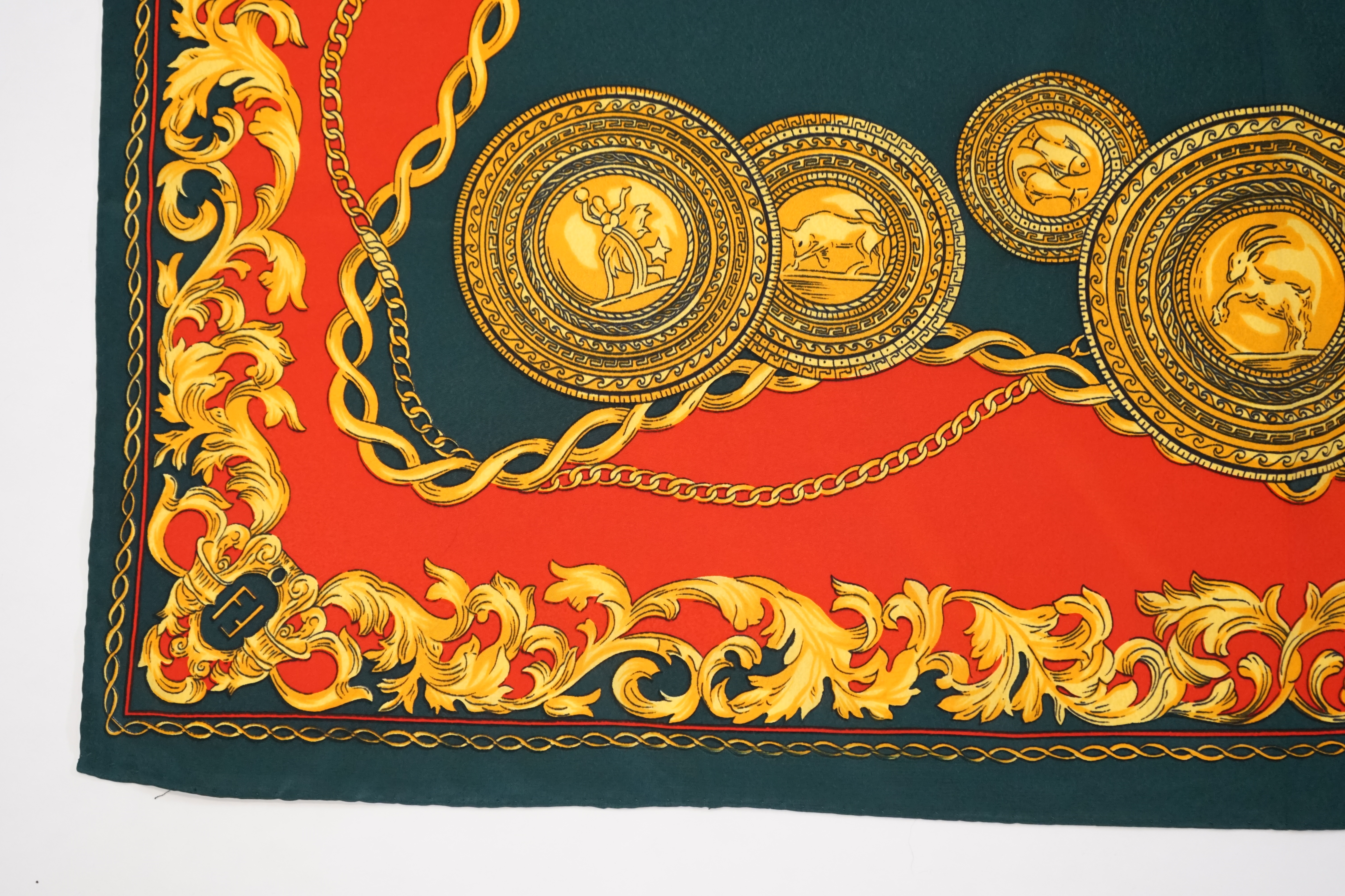A Hermès silk scarf decorated with gold zodiac sign animals and hybrids, gold foliage and chain design around the edges, 90 x 84cm